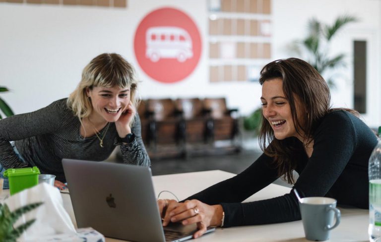 Two women working on laptop smiling